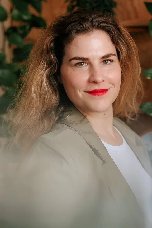 Business-Portrait einer Frau in professioneller Kleidung: Sie trägt ein elegantes, hellblaues Oberteil, lächelt freundlich und steht vor einem dezenten, grauen Hintergrund für Personal Branding Fotografie Business-Portrait einer Frau in professioneller Kleidung: Sie trägt ein elegantes, hellblaues Oberteil, lächelt freundlich und steht vor einem dezenten, grauen Hintergrund für Personal Branding Fotografie